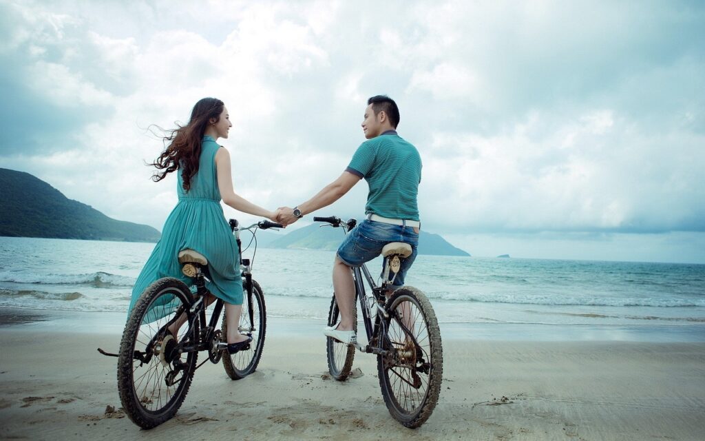 couple riding a bike together at the beach
